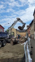 Ein Bagger hebt Erde aus. Es ist eine Baustelle zu sehen.